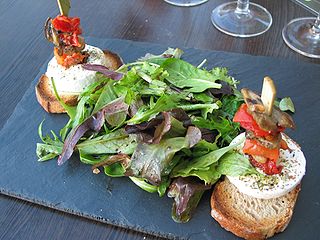 A photo of a mesclun salad and goat cheese on toasts.