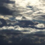 Photo of a cloudy sky with sun and dark clouds.